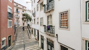 Eine enge Straße mit Häusern an beiden Seiten, eine Treppe, die nach oben führt, und eine Person, die geht.