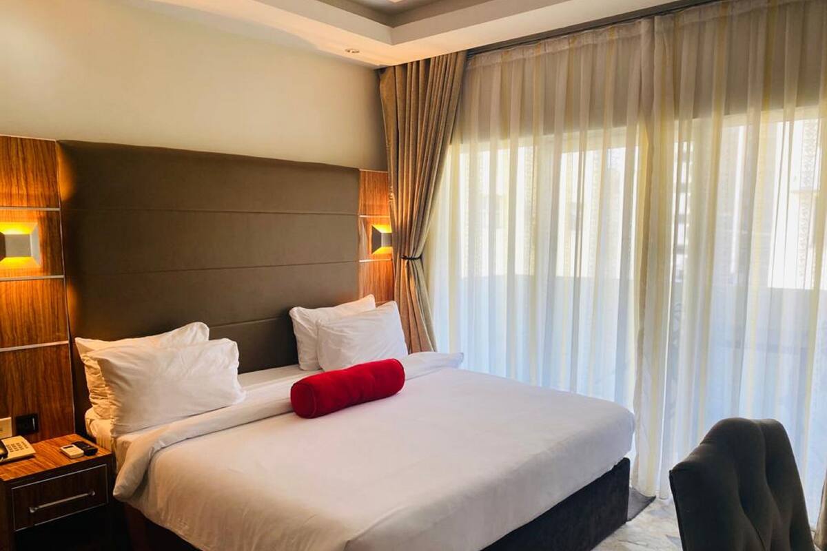 A hotel room with a large bed, a nightstand with a phone, and a chair.