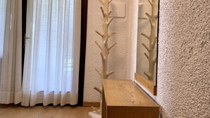 Una habitación con un escritorio de madera, un espejo y una puerta con cortinas blancas.
