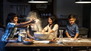 A group of people engaged in a baking activity at a wooden table with flour, a large mixing bowl, and various baking ingredients. - Ancient luxury oil mill (Ortonovo)