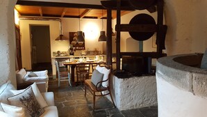 A cozy living area with a stone fireplace, a dining table set for four, and a comfortable seating arrangement. - Ancient luxury oil mill (Ortonovo)
