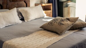 A neatly made bed with a grey bedspread, beige and brown pillows, and a beige throw blanket. - Ancient luxury oil mill (Ortonovo)