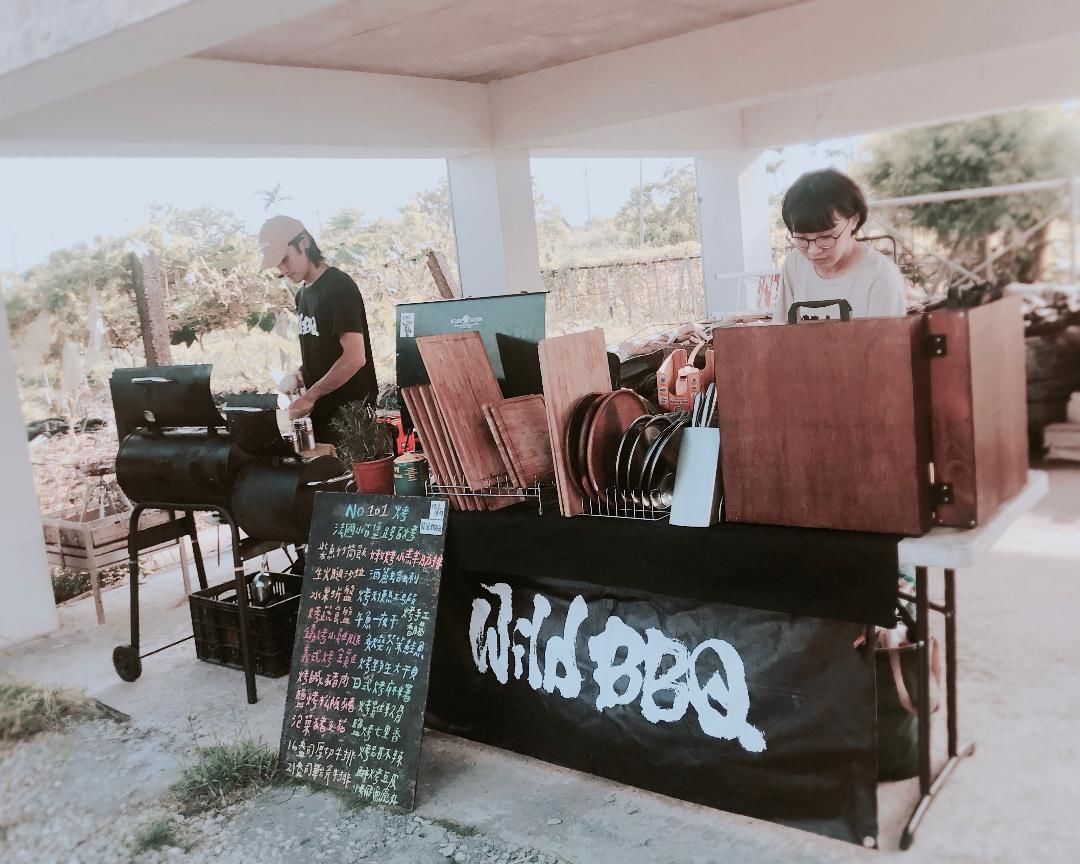 An outdoor barbecue setup with a sign reading "Wild BBQ".