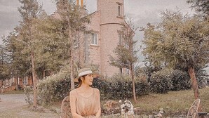A woman in a dress sitting at a table with a suitcase and a sign that reads "Palace Hotel." - Chateau de france (Wujie)