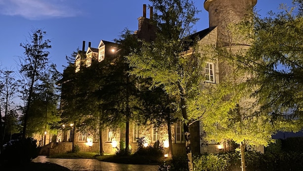A historic building with a prominent tower, surrounded by trees and illuminated by warm lighting. - Chateau de france (Wujie)