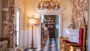 A grand hallway with a chandelier, checkered floor, and a fireplace with a red upholstered chair. - Chateau de france (Wujie)