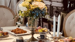 A dining table set with various dishes, a vase of flowers, and candles. - Chateau de france (Wujie)