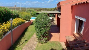 A red-roofed building with a pool, surrounded by greenery and a clear sky.