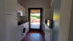 A compact kitchen with a washing machine, a stove, and a microwave.
