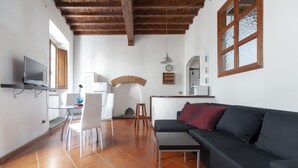 A living room with a black sofa, a dining table with chairs, a TV, and a kitchen area with a microwave. - Independent 50 meters from the central and very Tuscan Duomo (Firenze)