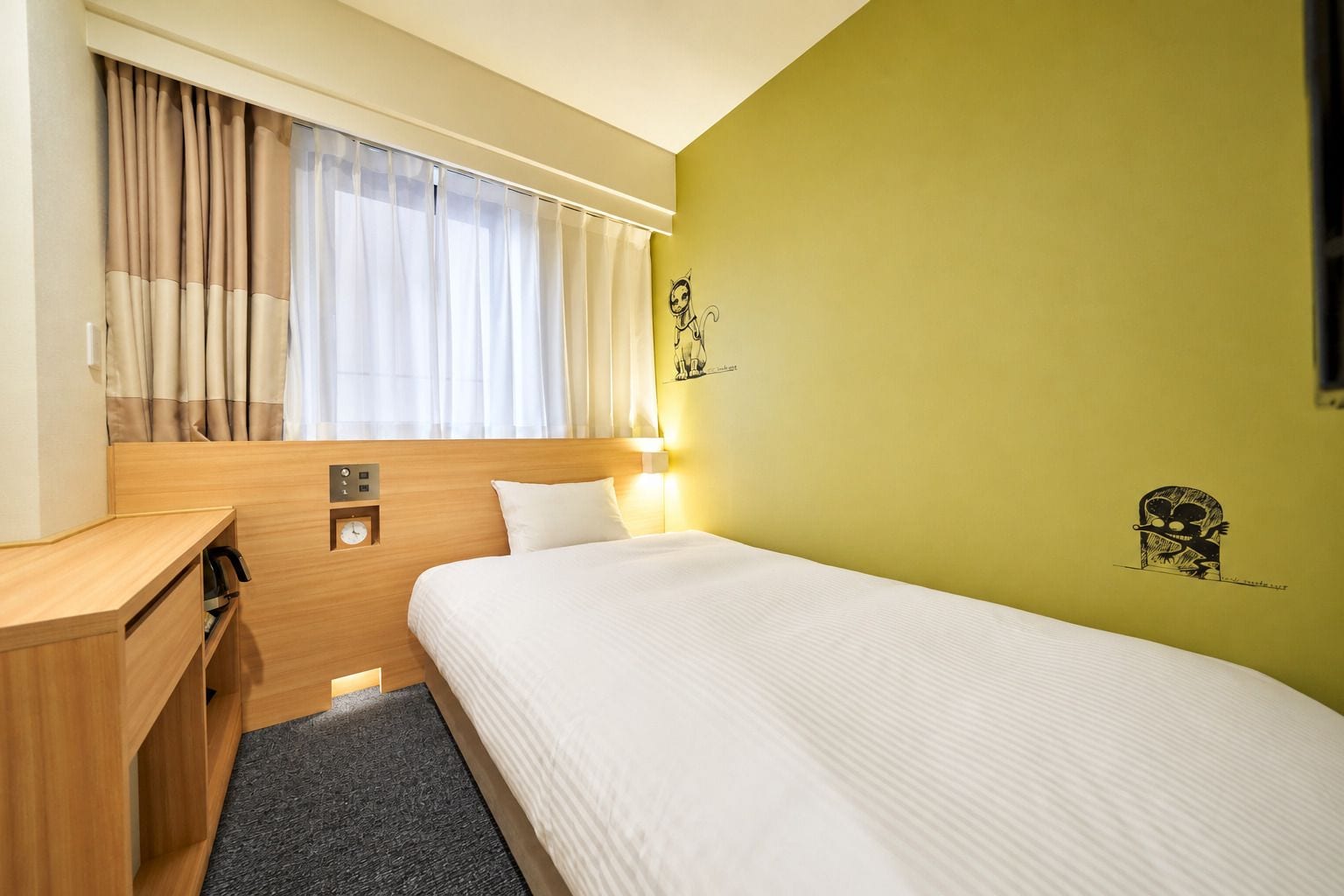 Una habitación de hotel con una cama, un escritorio, un reloj y una pared decorada con un personaje de dibujos animados.