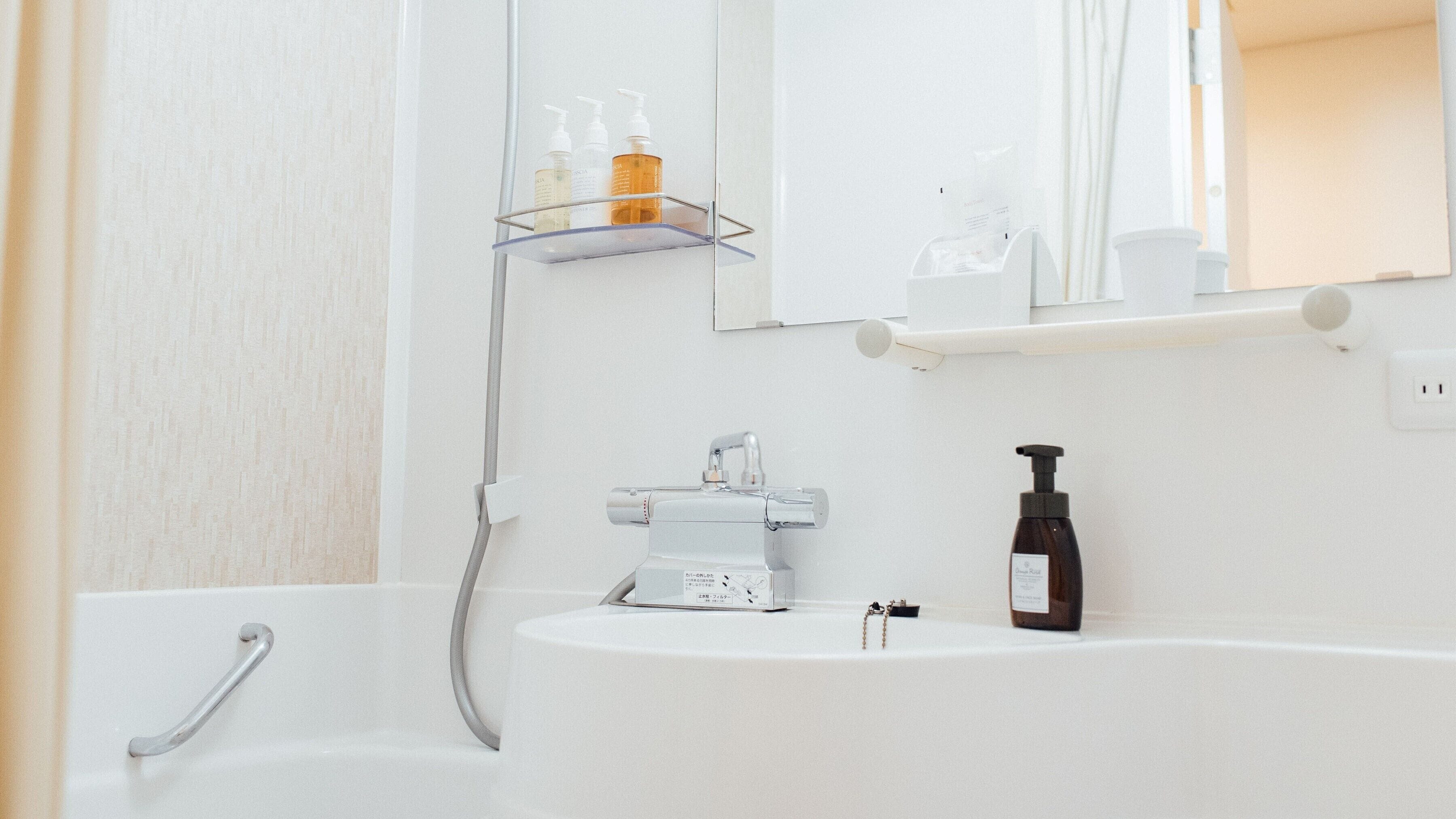 A modern bathroom with a white sink, a handheld showerhead, and a mirror above the sink.