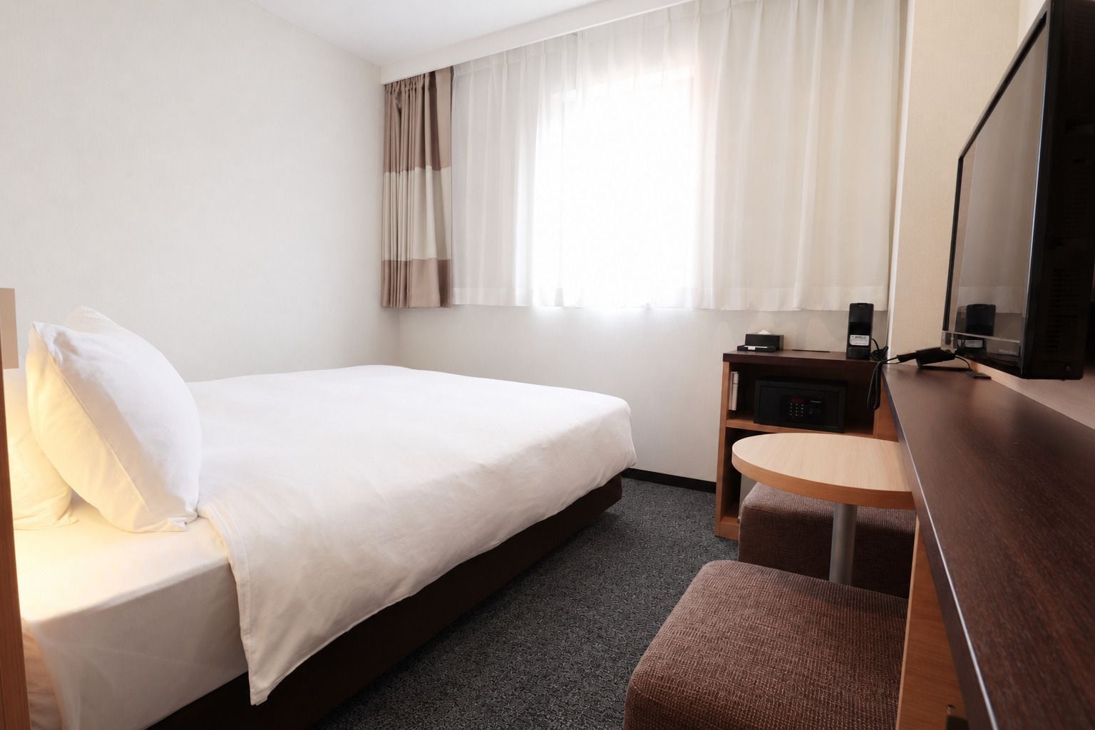 Una habitación de hotel con cama, escritorio, silla y televisión.