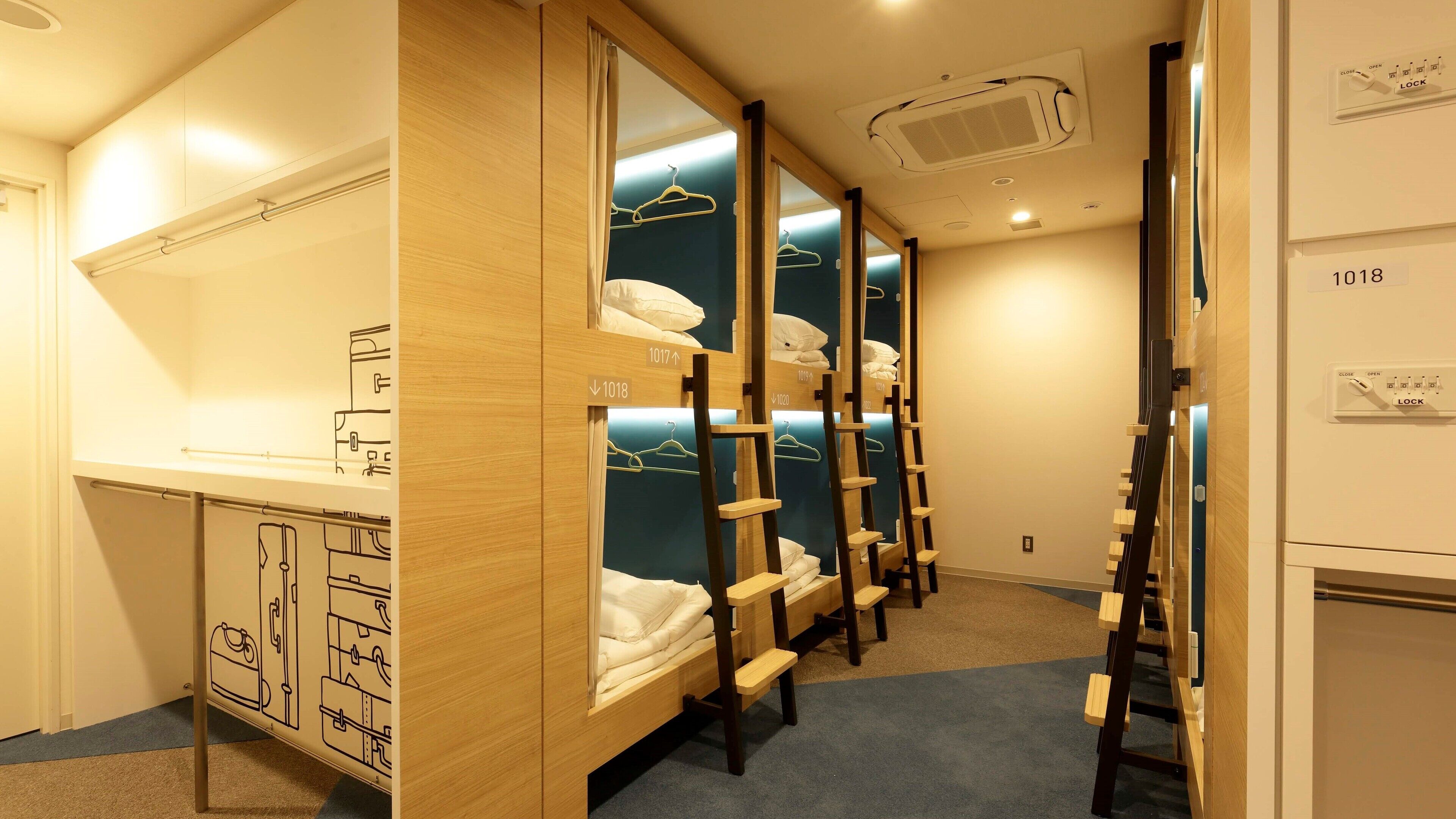 Una habitación de hotel con literas, un armario y un espejo.