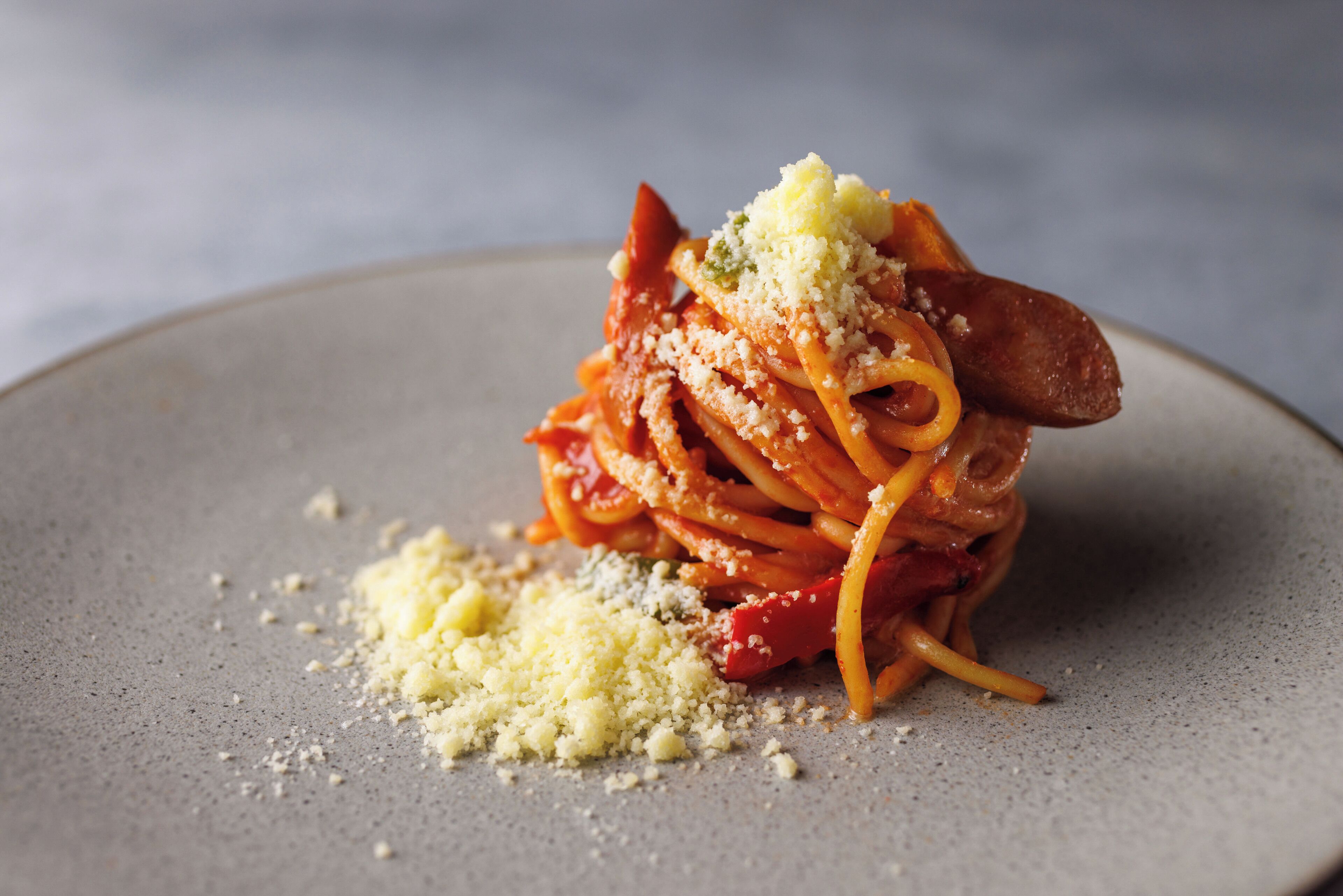 A plate of spaghetti with meat and grated cheese.