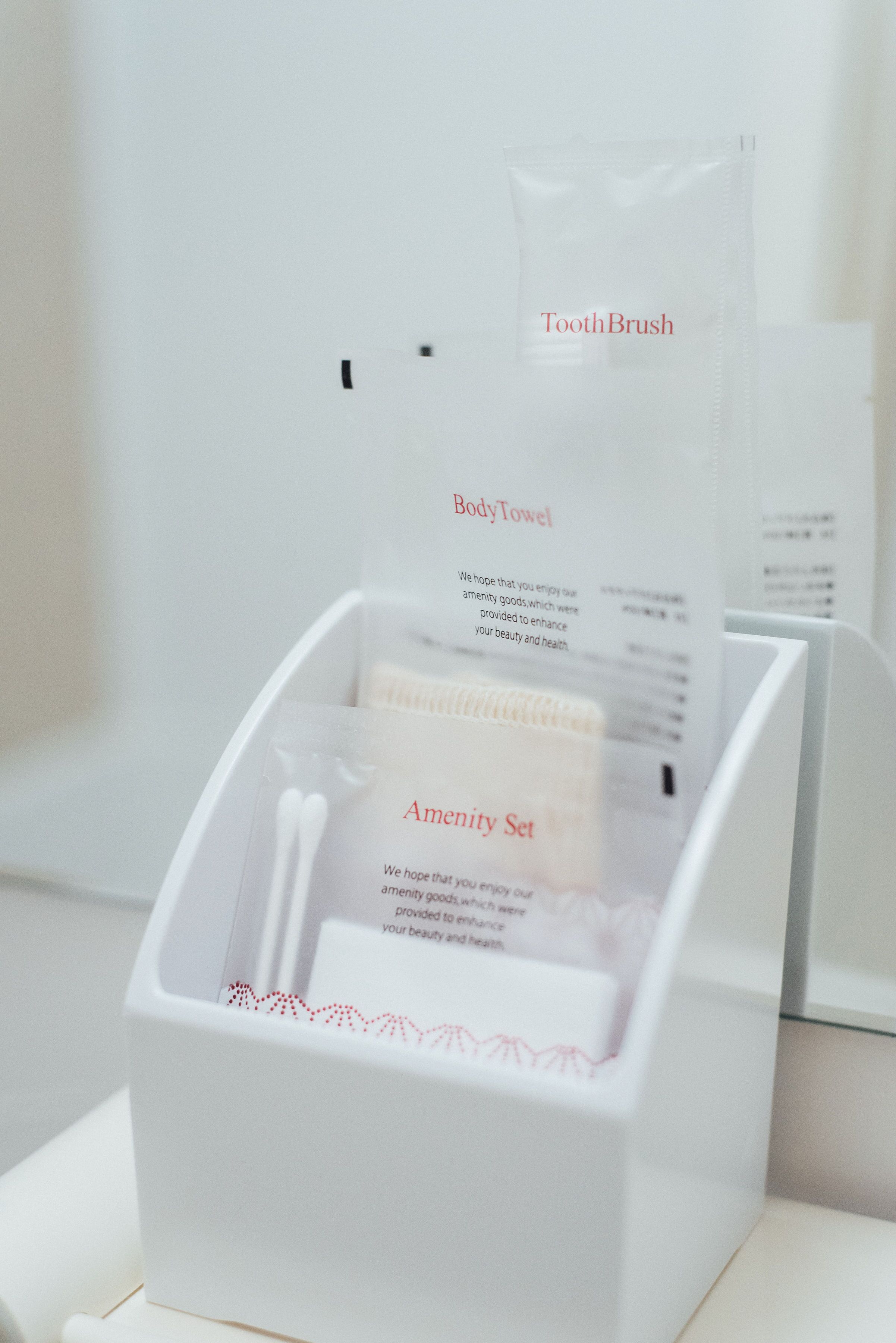 Caixa branca com escova de dentes, toalha de banho e kit de amenidades.