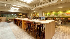 A modern bar area with stools, a counter, and a mural in the background. - WeBase TAKAMATSU - Hostel (Takamatsu)
