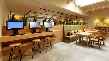 A modern cafe with multiple computer workstations, a green sofa, and a mural on the wall.