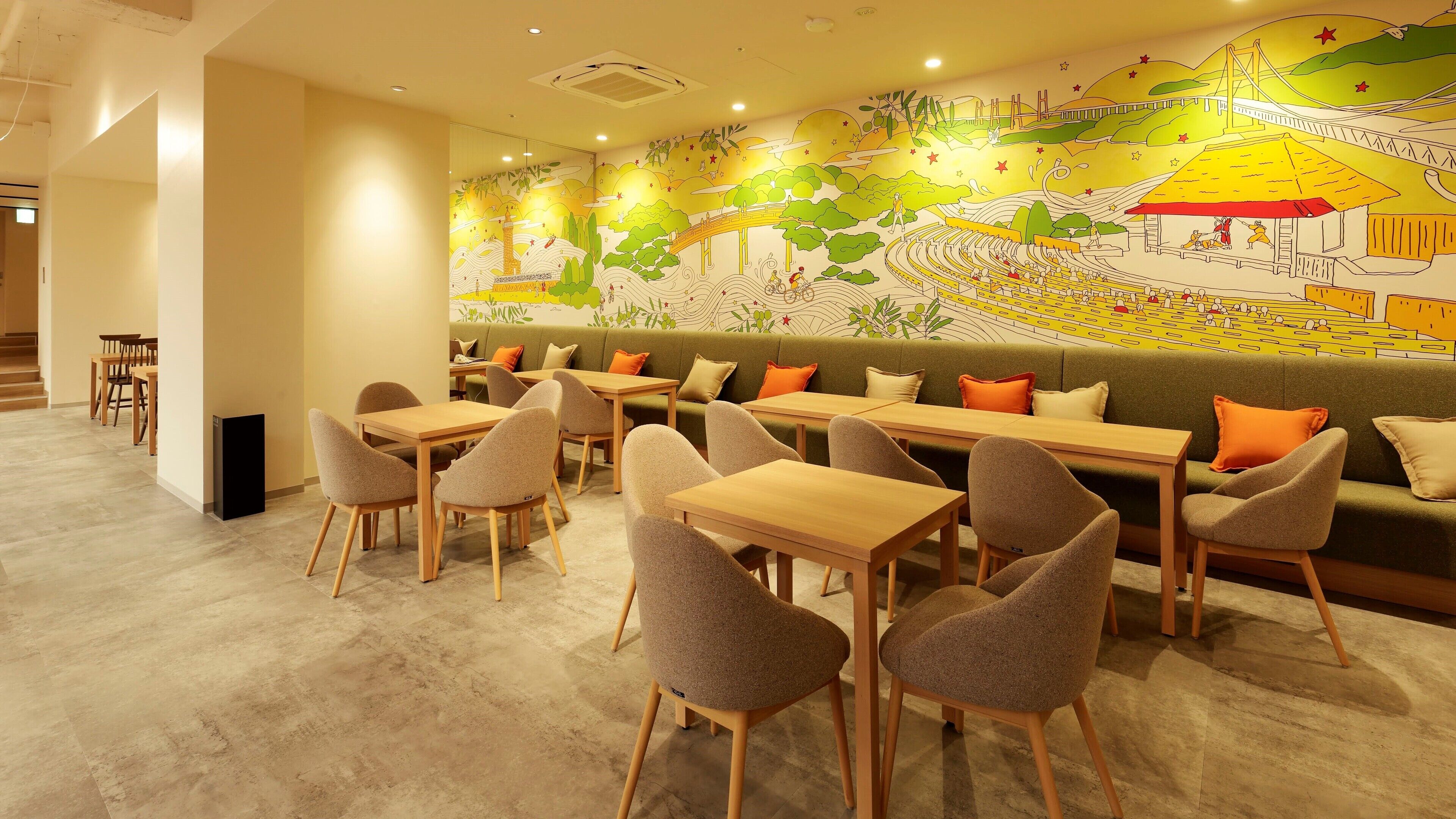 Un restaurante con un mural, mesas de madera y asientos acolchados.