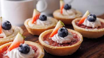 Una selección de tartaletas de frutas con crema batida y frutos rojos sobre una tabla de madera.