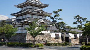 A traditional Japanese castle with multiple tiers, stone walls, and surrounding greenery. - WeBase TAKAMATSU - Hostel (Takamatsu)