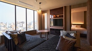 A hotel room with a city view, a bed, a sofa, a TV, and a small table. - WeBase TAKAMATSU - Hostel (Takamatsu)