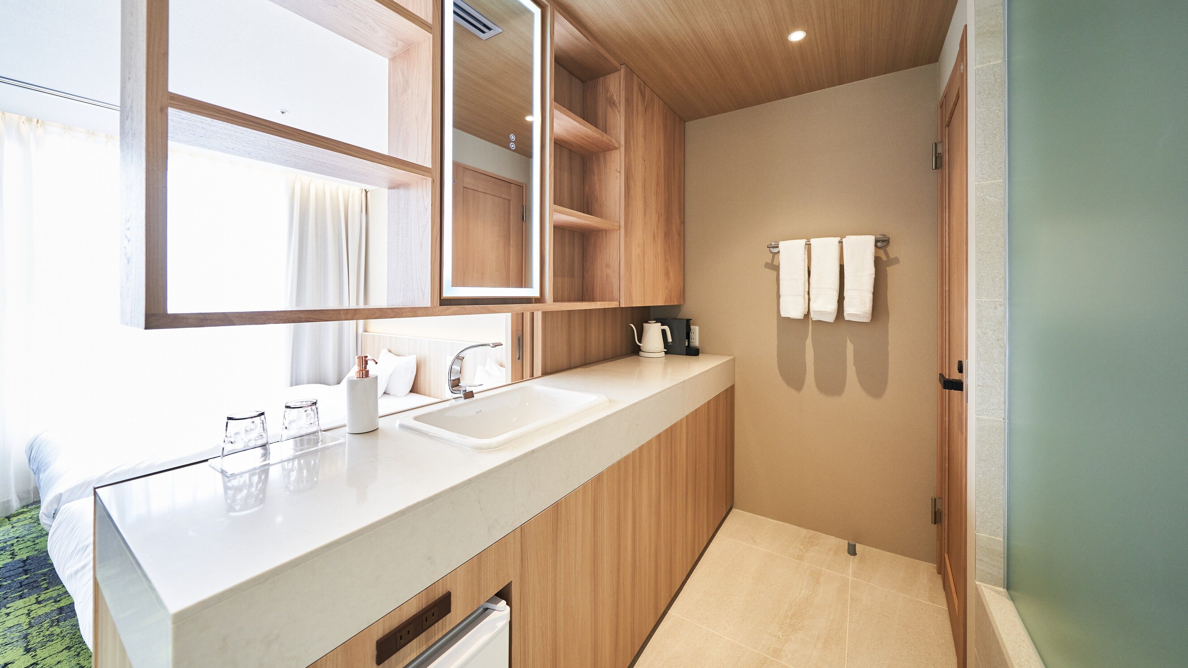 A modern bathroom with a large mirror, wooden cabinets, a white sink, and a towel rack.