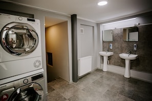 A modern bathroom with a built-in washing machine, two sinks, and a mirror. - Viking Hostel (Tbilisi)