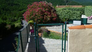 Een balkon met uitzicht op een rivier, een bloeiende roze boom en een bergachtig landschap.