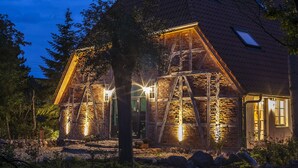 Un edificio de piedra con techo inclinado y varias ventanas, con fachada bien iluminada.