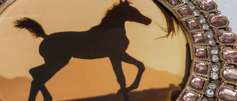 Een speld met een silhouet van een paard en een decoratieve rand.