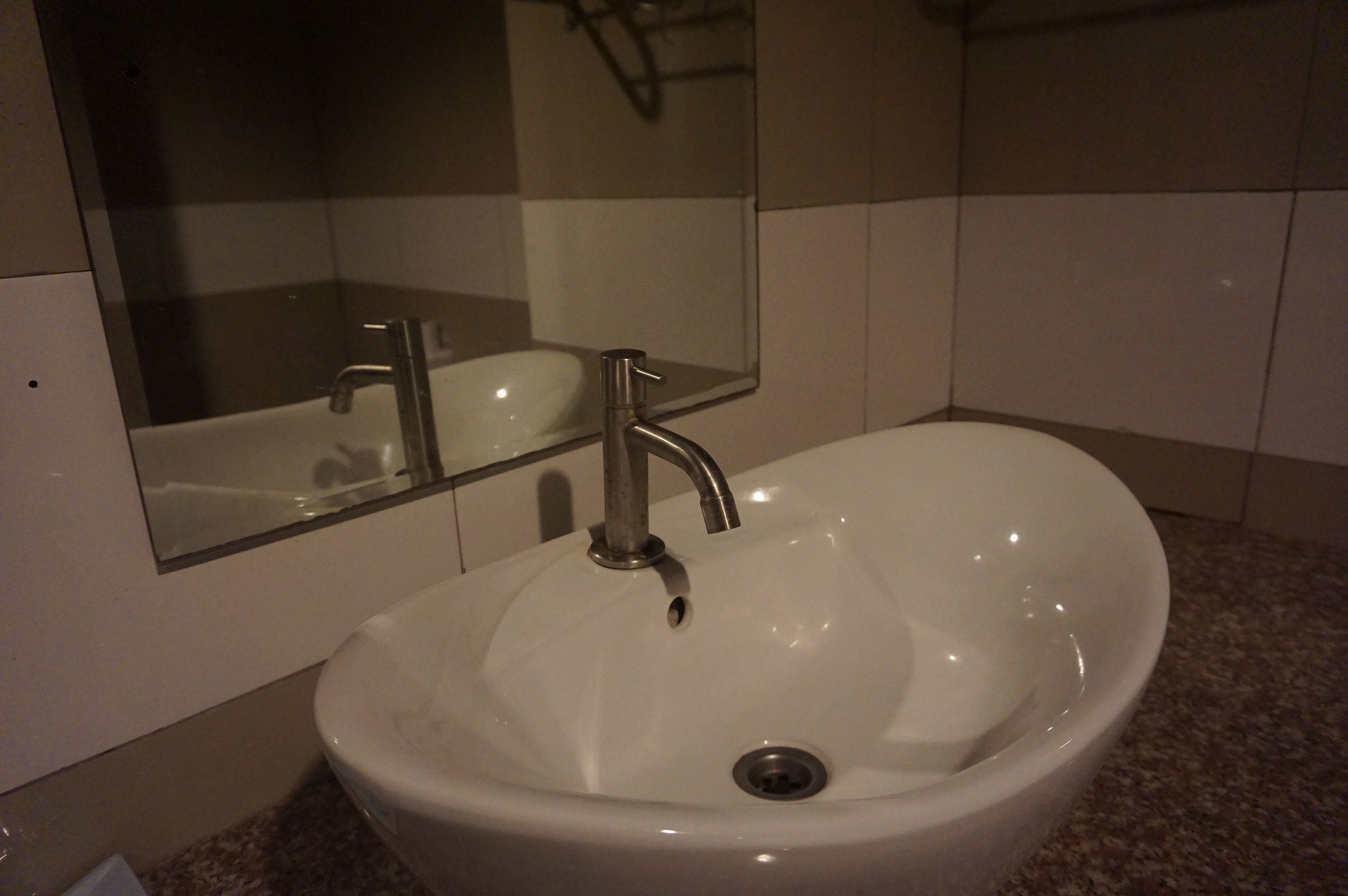 A bathroom with a white sink, a mirror, and a shower enclosure.