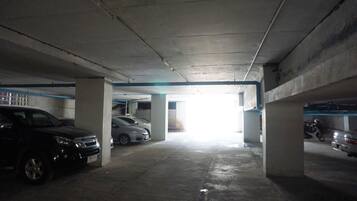Eine Tiefgarage mit Betonpfeilern, mehreren parkenden Autos und einem hellen Ausgang.