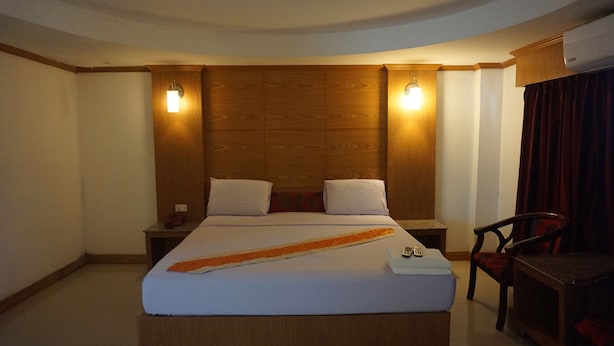 A hotel room with a large bed, two bedside tables, a chair, and a desk. - PP Hotel Dannok (Sadao)