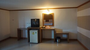 A small, compact room with a desk, a television, a refrigerator, and a mirror. - PP Hotel Dannok (Sadao)