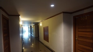 A hallway with a wooden door labeled "502" and a light fixture on the ceiling. - PP Hotel Dannok (Sadao)