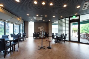 A spacious indoor area with multiple tables and chairs, large windows, and a ceiling with recessed lighting. - Hotel Arashiyama (Kyoto)