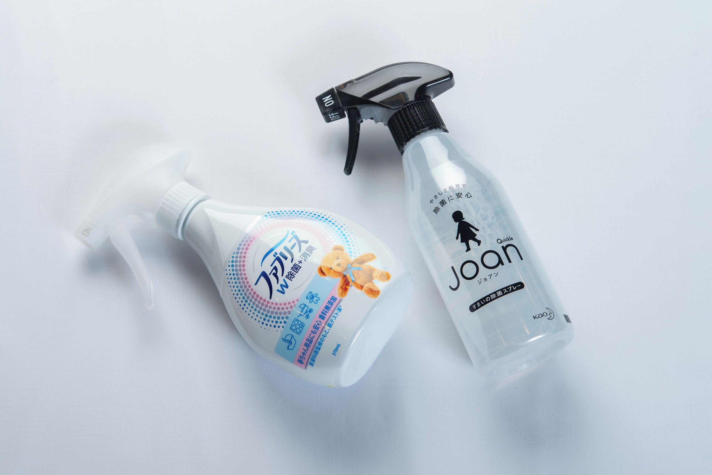 Two bottles of hand sanitizer, one with a pump and one with a spray nozzle, on a white surface.