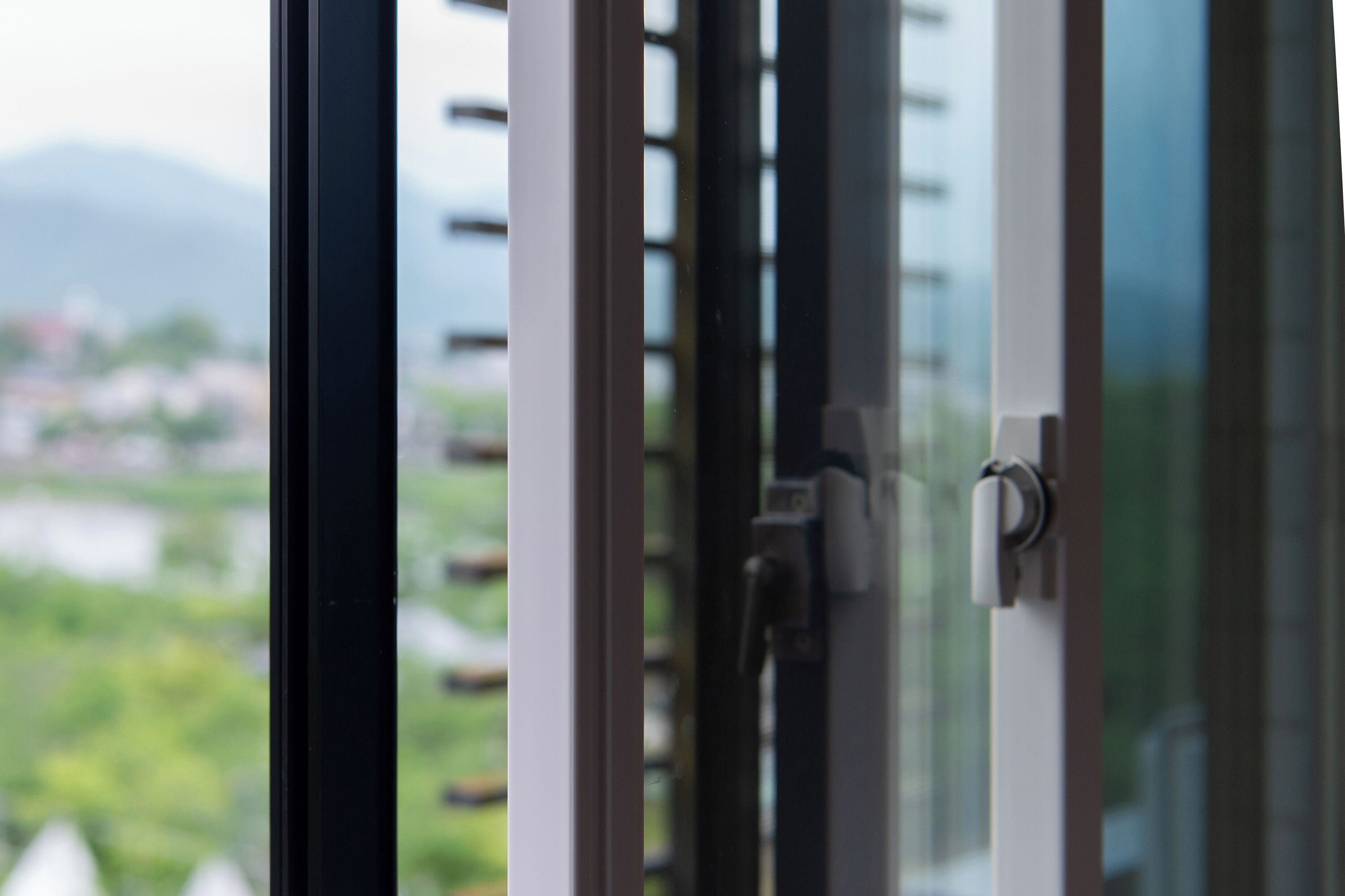 Blick durch ein Fenster auf eine grüne Landschaft und Gebäude in der Ferne.