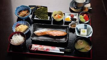 A traditional Japanese meal with various dishes including rice, fish, and soup, served on a black tray.