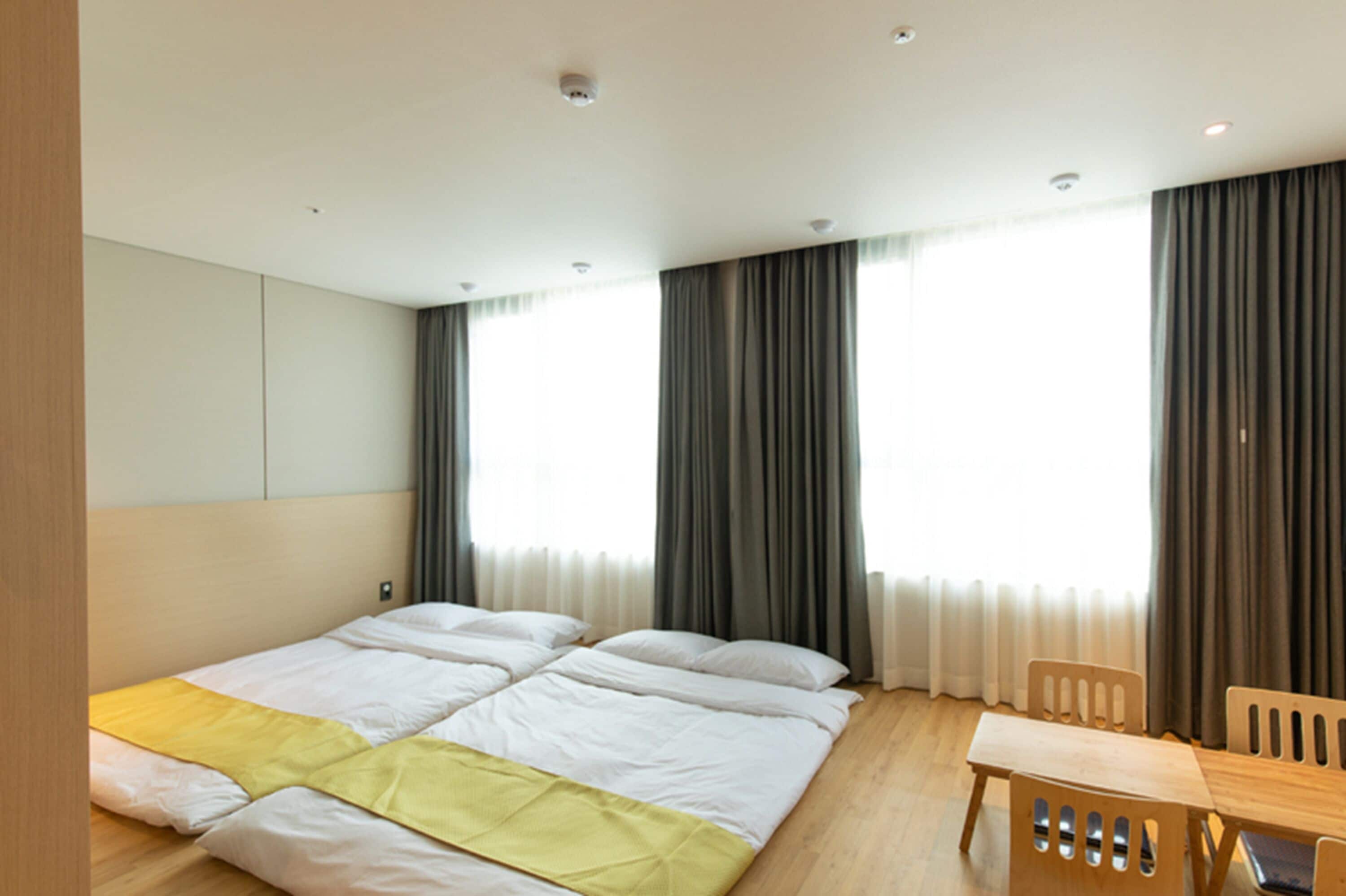 Une chambre d’hôtel avec un grand lit, un bureau en bois et une chaise.