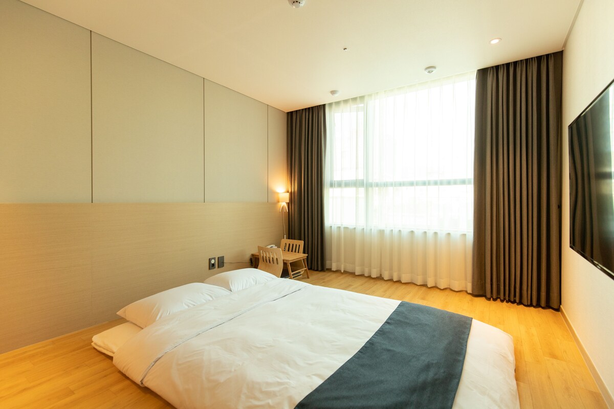 A hotel room with a large bed, a desk, and a TV.