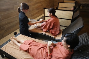 A massage therapy room with two massage tables, a wooden wall, and a tatami mat partition. - Blanc Art Misasa (Misasa)