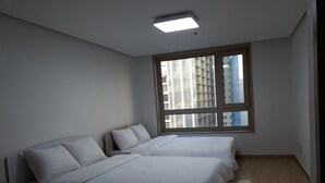 Un dormitorio con dos camas, un ventanal grande y una lámpara en el techo.