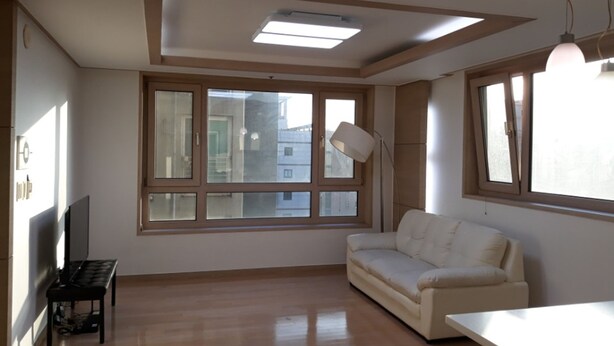 Una habitación con un ventanal grande, un sofá, una mesa y una lámpara.