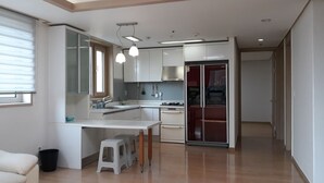 Una cocina moderna con armarios blancos, horno integrado y una zona de comedor con taburetes.