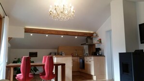 Eine moderne Küche mit Holzbalken, einer Kristallleuchter und einem Essbereich mit roten Stühlen.
