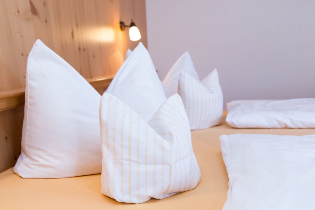 Ein Bett mit weißen Kissen und einem hölzernen Kopfteil.