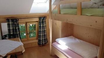 Una habitación pequeña y acogedora con una cama litera, un escritorio y una ventana con cortinas.
