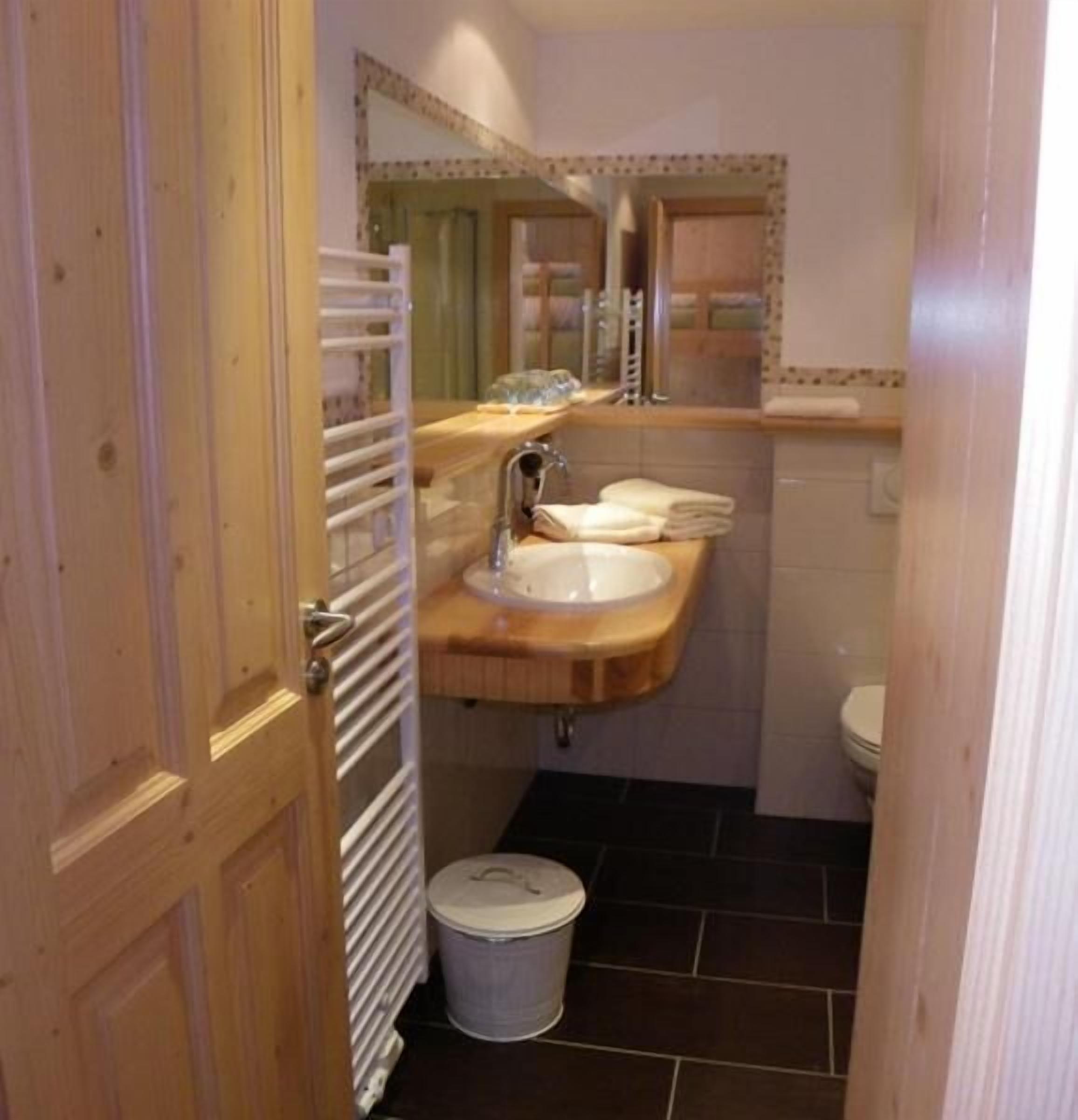Een kleine badkamer met een houten wastafel, een wastafel, een spiegel en een toilet.
